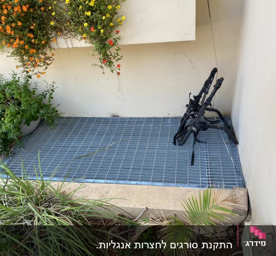 רשת מתכת על הרצפה עם מסגרת שחורה בצד